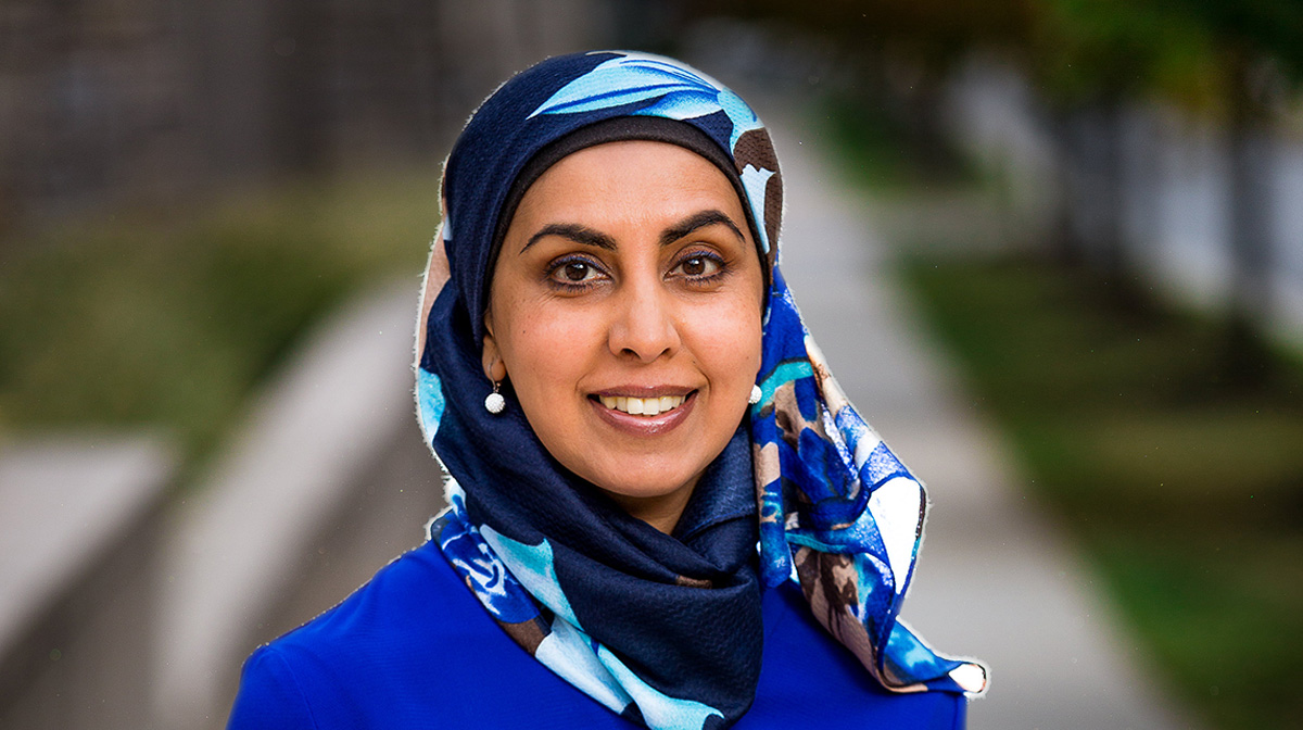 Canadian filmmaker and writer, Zarqa Nawaz, wearing a blue scarf and smiling in the foreground of a park